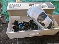 Open box showing chassis and unpainted shell with original carton labeled GT-4 RTR