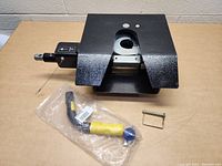 Primary photo showing the black 5th wheel gooseneck tow hitch, latch handle in packaging, and safety pin arranged on a table.