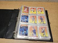 Photo of binder page showing 9 baseball cards, including multiple cards of Nolan Ryan and other players in vintage style with red and yellow backgrounds.