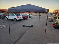 Front view of the EZ Up canopy tent fully set up on pavement with adjustable black legs and dark canopy top.