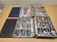 Open view of two binders laid flat, showing cards in plastic sleeves inside each binder.