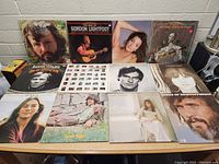 Overview photo showing 12 vinyl records laid out against a wall, featuring cover art of various artists including Kris Kristofferson, Gordon Lightfoot, and others.