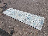 Full view of the runner rug laid out on asphalt showing the overall pattern and length.