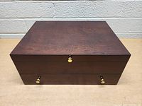 Top view of wooden flatware case showing smooth flat top surface and brass knobs on drawers.