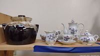 Vintage Roseville beanpot with drip glaze alongside Hal-sey Fifth Avenue floral tea set including teapot, creamer, sugar bowl, cups, and saucers.