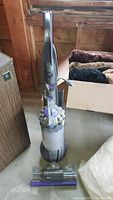 Front angled view of Dyson Ball Animal 2 upright vacuum, showing clear cyclone section and purple base head attachment, placed on concrete floor.