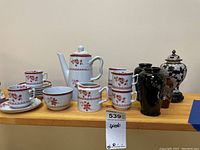 Full view of Spode tea set with teapot, cups, saucers, creamer and sugar bowl on left, Japanese vases on right, all on wooden shelf