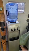 Full view of the water dispenser with large blue water jug on top, displaying overall condition and setup.