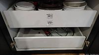 Top shelf with various white and off-white ceramic and glass casserole dishes and bakeware.