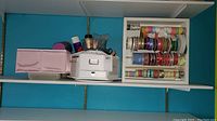 Shelf with pink fabric bins, white metal cash box, and small jars