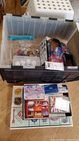 View of the plastic bin containing sandals and golf balls, with NHL Monopoly game and playing cards laid out in front.