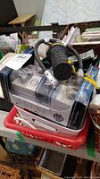 Overview photo showing two bins filled with various hardware items including cords and a black flashlight, along with a pack of hardware in plastic packaging.