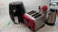 Philips black air fryer, stainless steel and red toaster, electric kettle on countertop