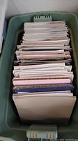 Top view of bin containing scrapbook albums and pages in various colors and sizes, tightly packed.