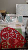 Photo showing a basket with various scrapbooking sticker sheets and cutouts, including a visible decorative red heart piece
