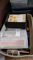 Full view of bin with mixed scrapbooking supplies including labeled bin and various items contained inside.