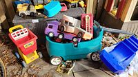 Overall lot showing blue plastic wagon, various toy trucks, and plastic bin