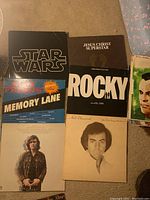 Top-down photo showing 7 visible album covers including Star Wars, Jesus Christ Superstar, Rocky, Neil Diamond, and Friends Memory Lane albums.