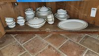 Shelf with full Brentwood China set including cups, plates, saucers, covered serving dishes and serving tray.