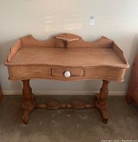Front view of rustic wood desk showing curved edges, single white knob drawer, detailed carved legs, and stretcher beam.