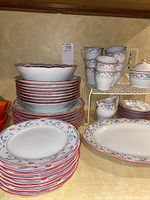 Stack of dinner plates, salad plates, and bowls showing floral pattern and red rim