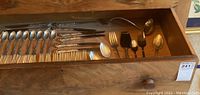 Photo of drawer with flatware including forks, spoons, salad spoons, knives, and serving pieces showing ornate handle designs.
