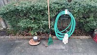 Garden hose coiled on metal stand with small garden statue and metal garden decor pieces on ground