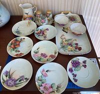 Photo of the full set showing pitcher, nine floral dishes and salt and pepper shakers arranged on table