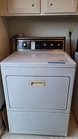Full front view of Kenmore front load dryer showing door and control panel with wood grain finish.