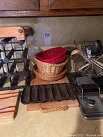 Wooden wine rack, woven baskets, cast iron corn tray, cutting boards, and metal kitchen toaster on countertop.