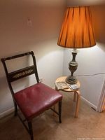 Brass lamp, wooden side table, vintage chair in a corner with marble ashtray and coasters on the table, ambient lighting.
