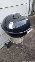 Front angled view of the black Weber charcoal kettle grill showing the round body, handles, and wheels.
