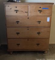 Front view of oversized wooden chest with five drawers and metal handles.
