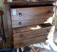 Front view of wooden chest with four drawers partially open showing round wooden knobs and cutlery inside one drawer. Lot stickers on drawers indicating lot number.