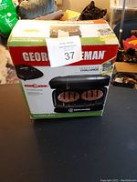 Closed box of George Foreman Mini Grill showing branding and grilling image on box.