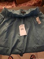 Photo of a light blue skirt laid flat showing the gathered elastic waistband and textured dot fabric pattern.