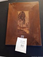 Rectangular wooden picture with a tree scene in the center panel framed by smooth wooden border, minor corner wear visible.