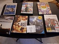 Photo of 7 DVDs laid out on table showing front covers of each DVD case, includes The Mentalist Season 3, A Muppet Christmas, Looney Tunes, Childhood's End, Deceit, Dead Zone Season 1, and This Christmas