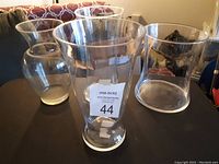 Photo showing three clear glass flower vases of different shapes on a table.