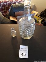Photo of clear glass liquor decanter with diamond cut pattern and matching stopper beside it.