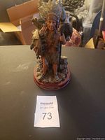 Front and side view of Native American chef ornament with staff and bird on wooden base