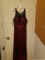 Full view of red women's dress hanging on hanger showing length and silhouette