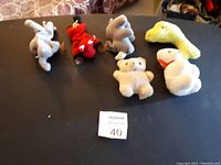 Seven assorted stuffed animal plush toys laid out on a surface, showing good condition.