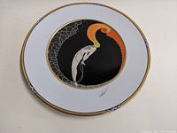 Full front view of the Erté charger plate showing the entire artistic design titled L'Amour with a white plate border and gold trim with purple accents.