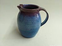 Photo of the 6-inch art pottery pitcher showing side profile, handle, and spout with purple to blue gradient glaze.