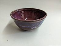 Front-side angle of purple studio pottery bowl with glossy finish showing interior and exterior glaze