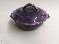 Side angle showing purple and brown glazed covered casserole with handles