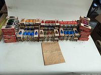 Photo showing 23 boxes of colored D-14 C-9 1/2 holiday light bulbs laid out on a surface, colors include blue, red, pink, green, and orange. Boxes vary in cardboard condition but are original.
