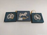 All three Lenox Christmas ornaments displayed in original blue boxes: rocking horse, angel with instrument, and cat in circular design.