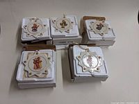 Five star-shaped ceramic ornaments arranged in original molded Styrofoam packaging, all with vintage M.J. Hummel designs and gold star accents.